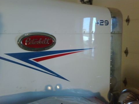 2003 Peterbilt 379 - Close-up of a white Peterbilt truck hood showing the brand badge and a graphic stripe.