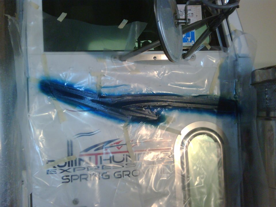 White semi-truck door masked with plastic for bodywork, blue paint repair area, 'Rollin Thunder Express' decal