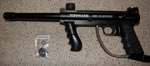 1994 Ford Bronco - A black Tippmann 98 Custom paintball marker is shown with a small bag of spare parts next to it.