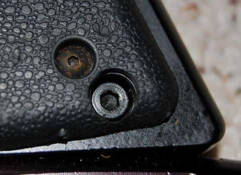 1994 Ford Bronco - Two hex screws are visible on a textured plastic surface, one showing signs of rust.