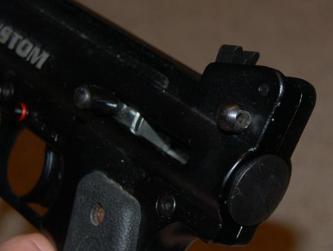 1994 Ford Bronco - A detailed view of a black firearm component, showing mechanical parts and some text.