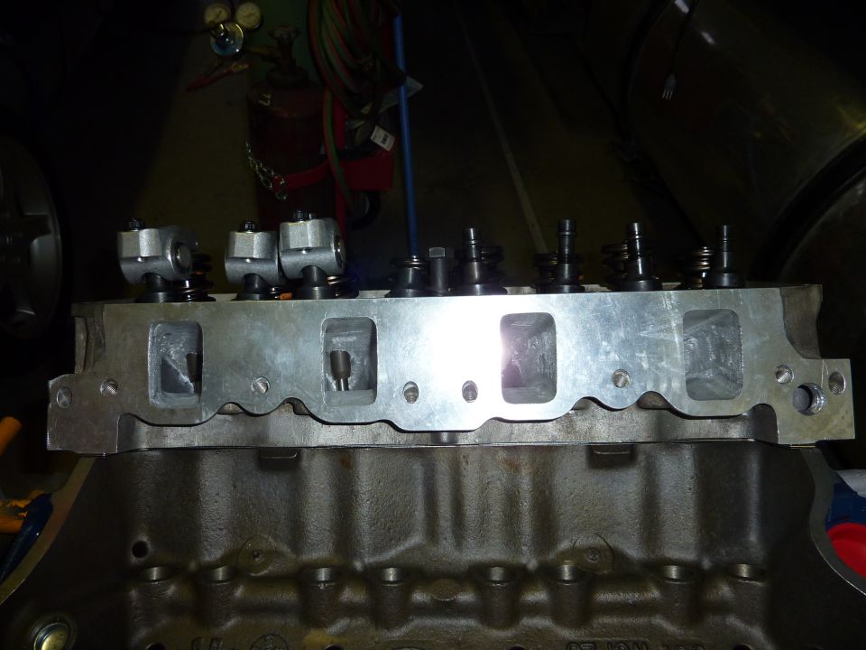 Close-up of an engine cylinder head with rocker arms installed, sitting on top of an engine block
