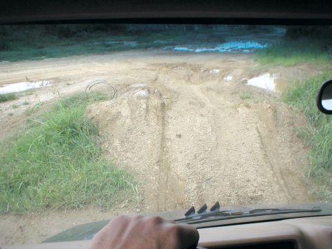 1983 Ford Bronco - Navigating a challenging dirt road with water hazards and uneven terrain.