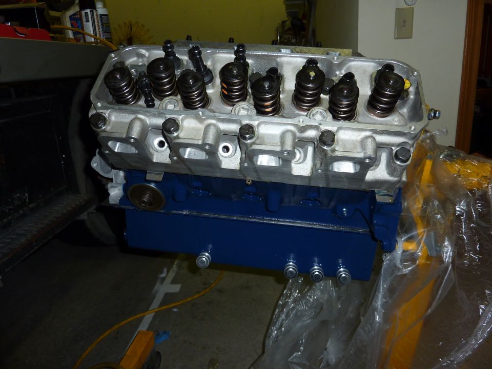 Blue engine block with silver cylinder head, showing valves and springs. Part of a vehicle engine