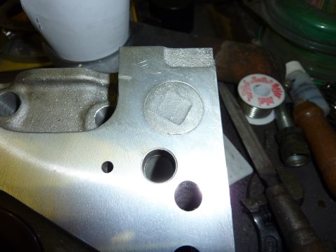 1971 Ford Mustang - Close-up of a metal engine component, possibly for a 1971 Ford Mustang, with various tools and soldering supplies in the background.