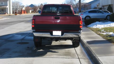 1997 Dodge 2500 - The rear of a red pickup truck is shown parked on a concrete driveway with a silver sedan in the background.