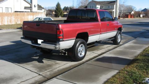 1997 Dodge 2500 - This red and silver pickup truck is shown from the rear, parked on a concrete driveway.