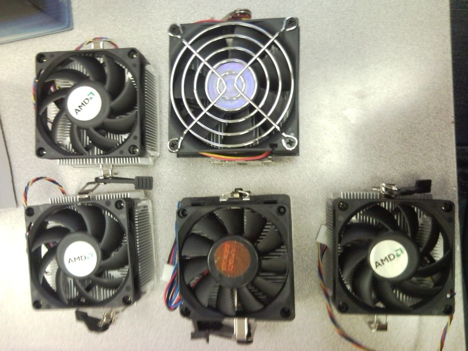 Five computer CPU coolers, some with AMD logos, arranged on a surface