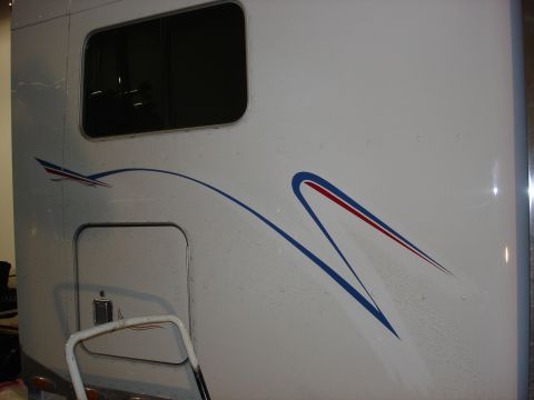 2003 Peterbilt 379 - Side view of a white semi-truck blue and red racing stripes and a prominent window.