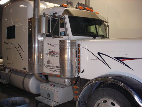 2003 Peterbilt 379 - Close-up of a white semi-truck's cab, showing custom decals and chrome detailing.