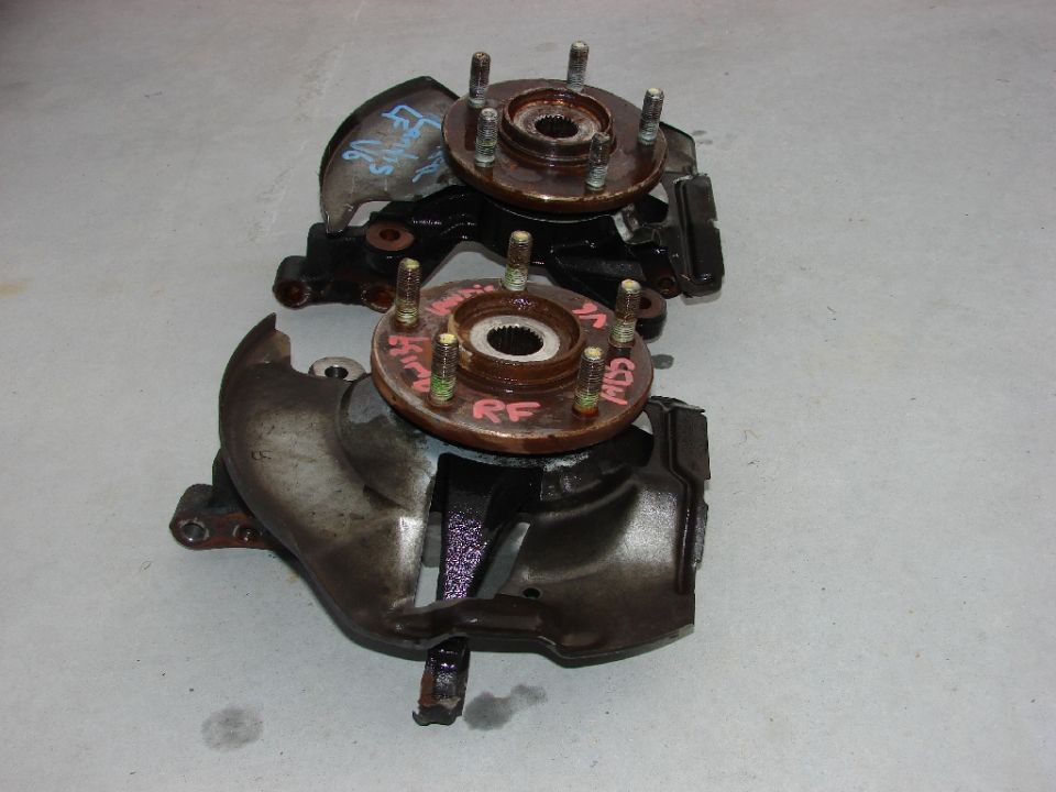 Two automotive front wheel hubs and knuckles, one marked LF, the other RF