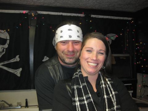 2006 Harley-Davidson Sportster Custom - A man and woman pose for a photo with a pirate flag and festive lights in the background.