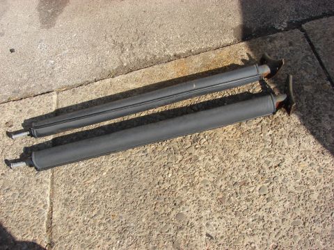 1996 Jeep Grand Cherokee - Two black roof rack rails are shown lying on a concrete surface, likely removed from a vehicle.