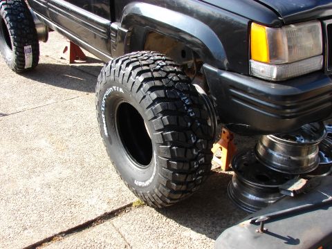 1996 Jeep Grand Cherokee - A 1996 Jeep Grand Cherokee is shown on jack stands, new off-road tires and spare rims ready for installation.