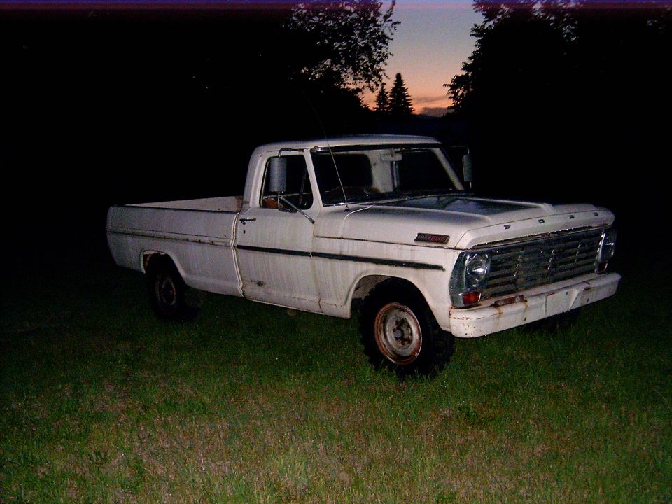 White 1967 Ford F-series pickup truck parked in grass at dusk