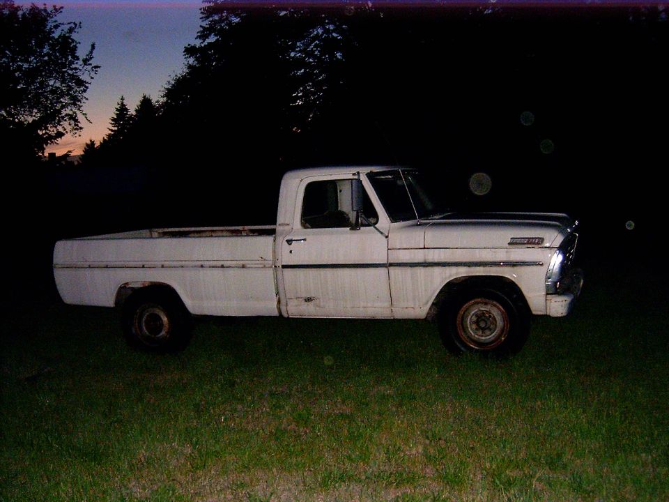 White 1970s Ford pickup truck parked on grass at dusk