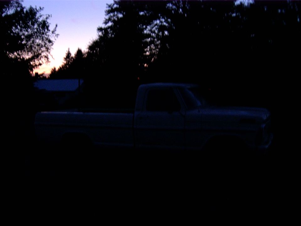 Pickup truck silhouetted against a twilight sky with trees in the background