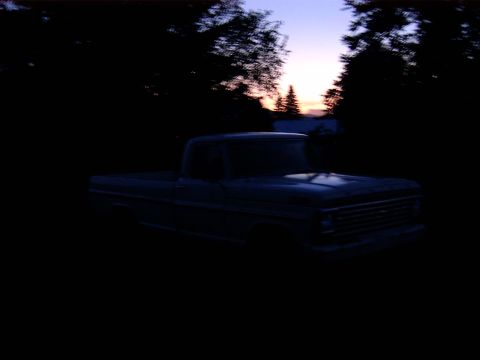 1988 Ford Bronco - A pickup truck sits in silhouette against a twilight sky, surrounded by trees.
