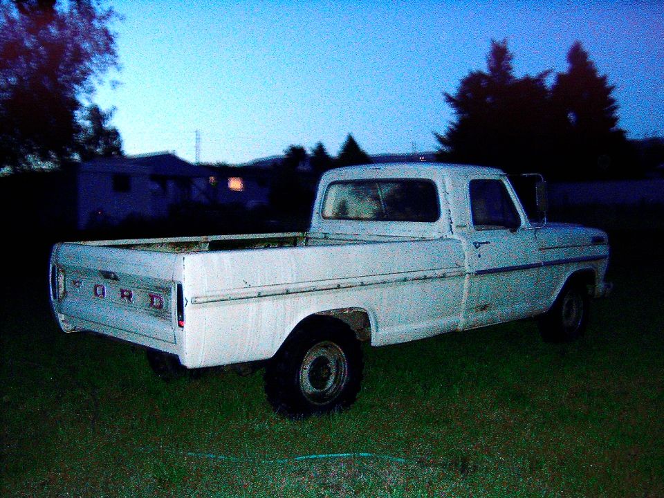 White Ford pickup truck, rear 3/4 view. Visible 'FORD' tailgate lettering