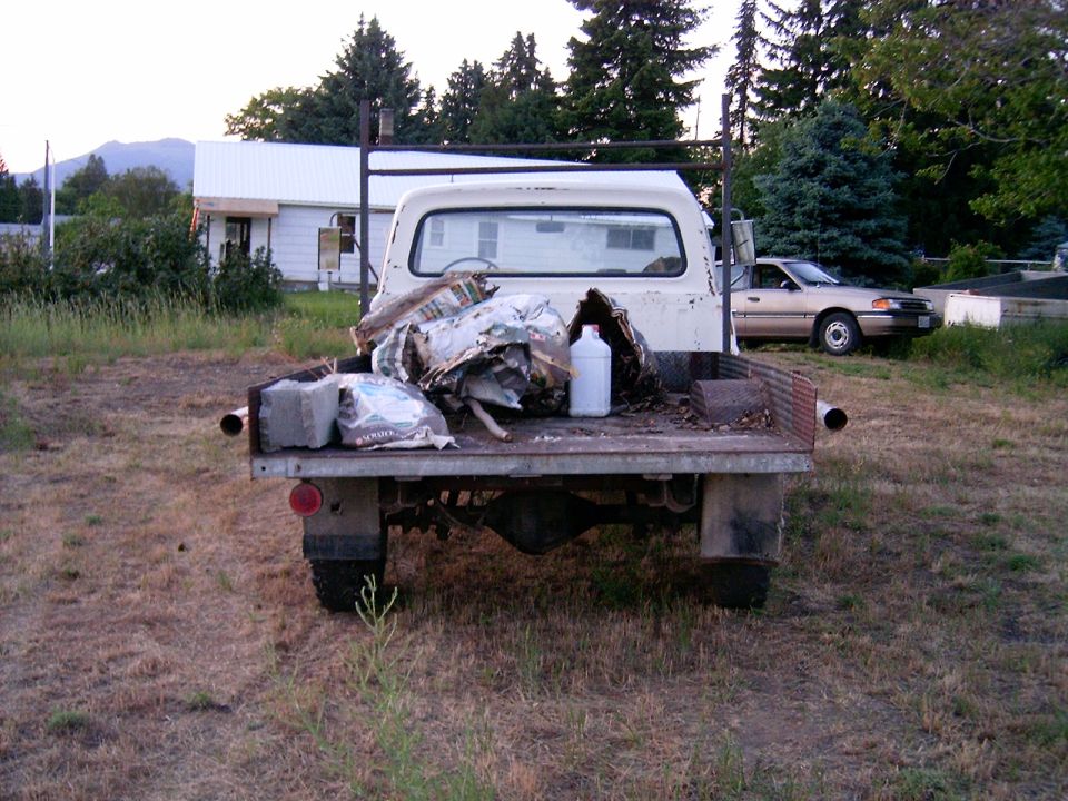 White pickup truck bed loaded with debris, including concrete blocks and a white bottle, viewed from the rear