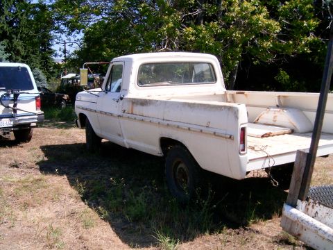 1988 Ford Bronco - A weathered white pickup truck sits in a grassy lot next to a white SUV.