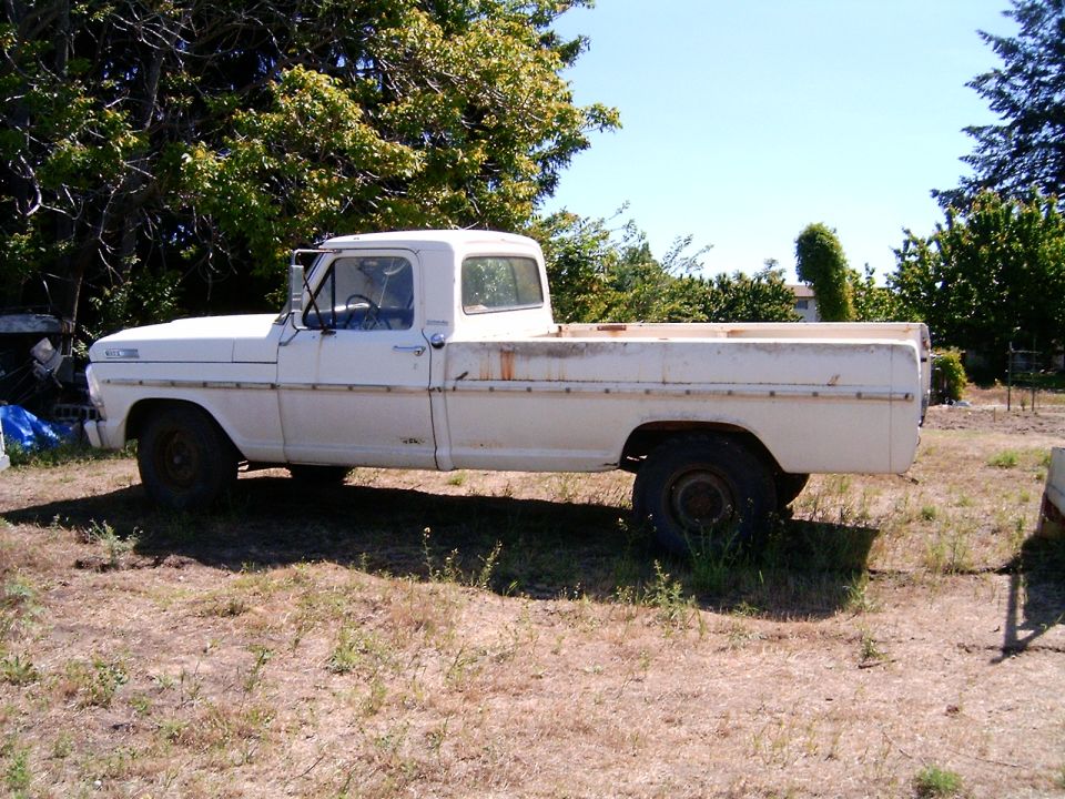 White pickup truck, side view, showing rust on the bed rails and faded paint