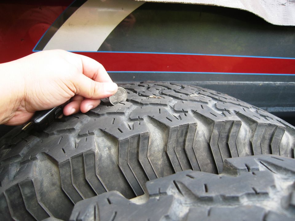 hand holding coin to check tire tread depth