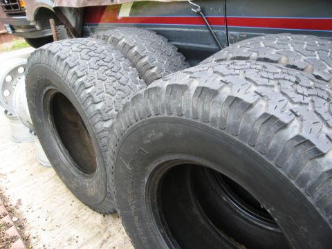 1986 Ford Bronco - A collection of off-road tires are displayed, with a vehicle partially visible behind them.
