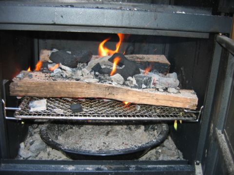 1992 Ford Bronco - A wood-burning stove contains logs and charcoal actively burning with flames visible.