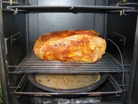 1992 Ford Bronco - A piece of meat is being smoked inside a smoker, with a pan below to catch drippings.