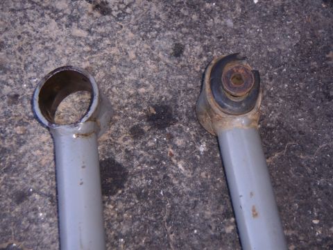 2003 Jeep Wrangler - Close-up view of two suspension control arms, one showing a worn rubber bushing and bolt assembly.