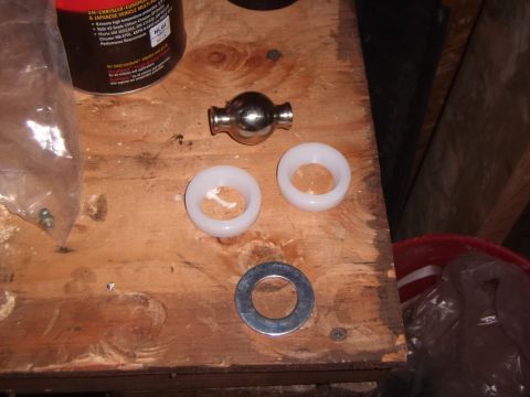 2003 Jeep Wrangler - Various automotive parts are laid out on a wooden workbench, including a ball joint and bushings.