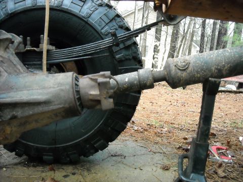 1979 Ford F-150 - Driveshaft and rear axle assembly of a vehicle, with a large tire visible.