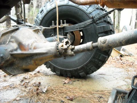 1979 Ford F-150 - Close-up view of a vehicle's rear axle, driveshaft, and tire, tire, with visible leaf springs.