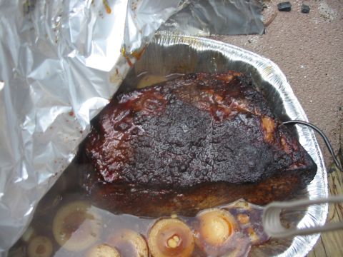 1992 Ford Bronco - A cooked brisket rests in a foil pan, partially covered by foil, with a meat thermometer inserted.