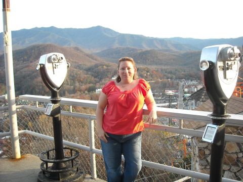 1979 Ford F-150 - A woman stands on a balcony overlooking a valley with mountains in the distance, with two viewing binoculars nearby.