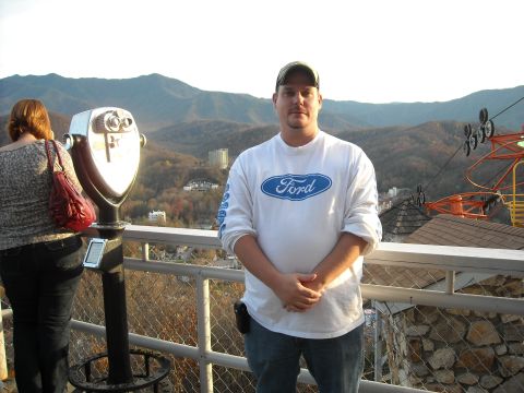 1979 Ford F-150 - Man wearing a Ford t-shirt stands on an overlook with mountains and a ski lift in the background.