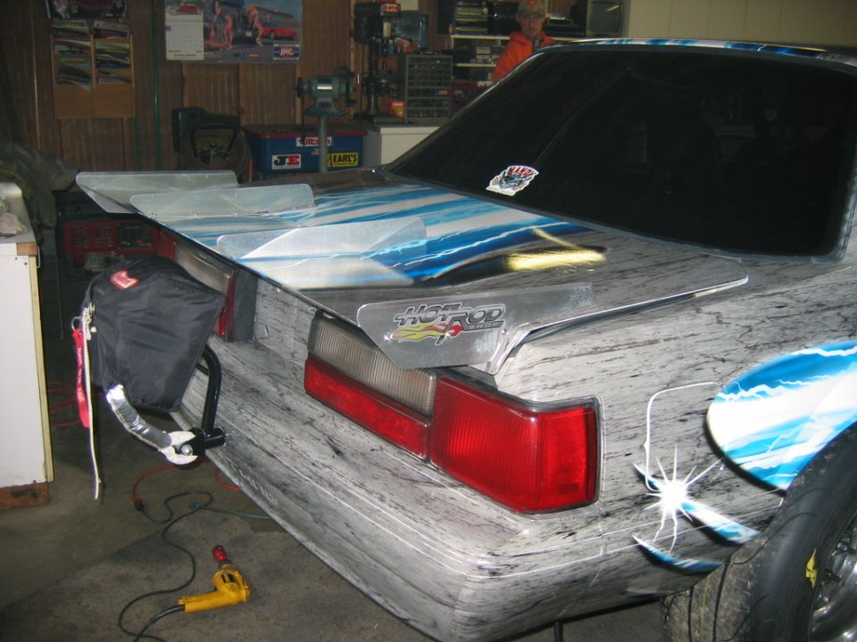 1992 Ford Mustang rear with custom paint and large spoiler. "HOT ROD" decal visible on spoiler