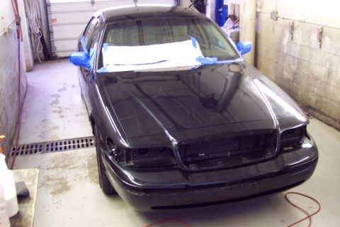 2001 Ford Crown Victoria - A black sedan is parked in a garage, undergoing some work with masking tape applied to its exterior.