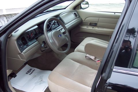 2001 Ford Crown Victoria - The interior of a 2001 Ford Crown Victoria shows tan cloth seats and a driver's side floor mat.