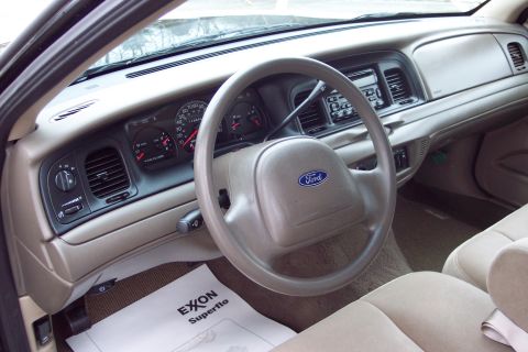 2001 Ford Crown Victoria - Dashboard and steering wheel of a 2001 Ford Crown Victoria, with an Exxon Superflo mat on the floor.