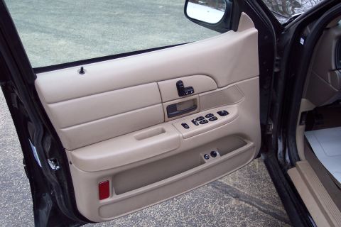2001 Ford Crown Victoria - Interior view of a tan door panel with power controls and a red reflector on a 2001 Ford Crown Victoria.