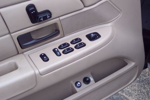 2001 Ford Crown Victoria - Close-up of the driver's side interior door panel, showing window controls and a door handle.