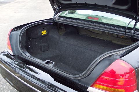 2001 Ford Crown Victoria - The spacious trunk of a black 2001 Ford Crown Victoria is open, revealing its carpeted interior.