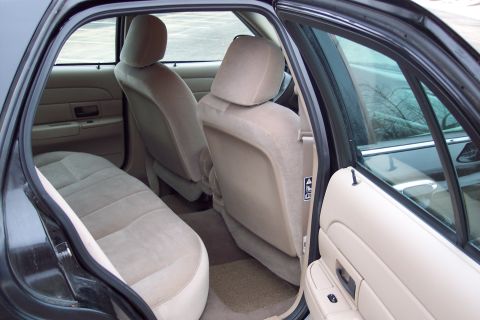 2001 Ford Crown Victoria - The interior of a 2001 Ford Crown Victoria, viewed from the rear passenger side, reveals tan cloth seats and door panels.