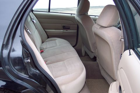 2001 Ford Crown Victoria - Rear interior view of a 2001 Ford Crown Victoria, showing tan cloth seats and door panels.