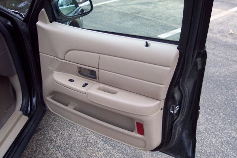 2001 Ford Crown Victoria - The interior door panel of a vehicle is shown, tan upholstery and black trim details.