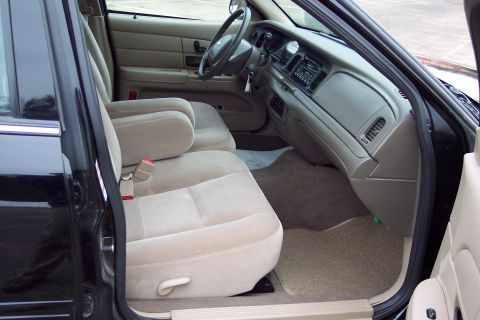 2001 Ford Crown Victoria - The interior of a 2001 Ford Crown Victoria features tan cloth seats and a beige dashboard with a factory radio.