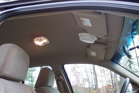 2001 Ford Crown Victoria - The interior ceiling of a car, dome lights and sun visors, with a view of trees outside.