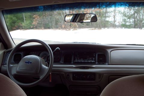 2001 Ford Crown Victoria - The interior of a 2001 Ford Crown Victoria, the steering wheel, dashboard, and a view of the snowy landscape through the windshield.